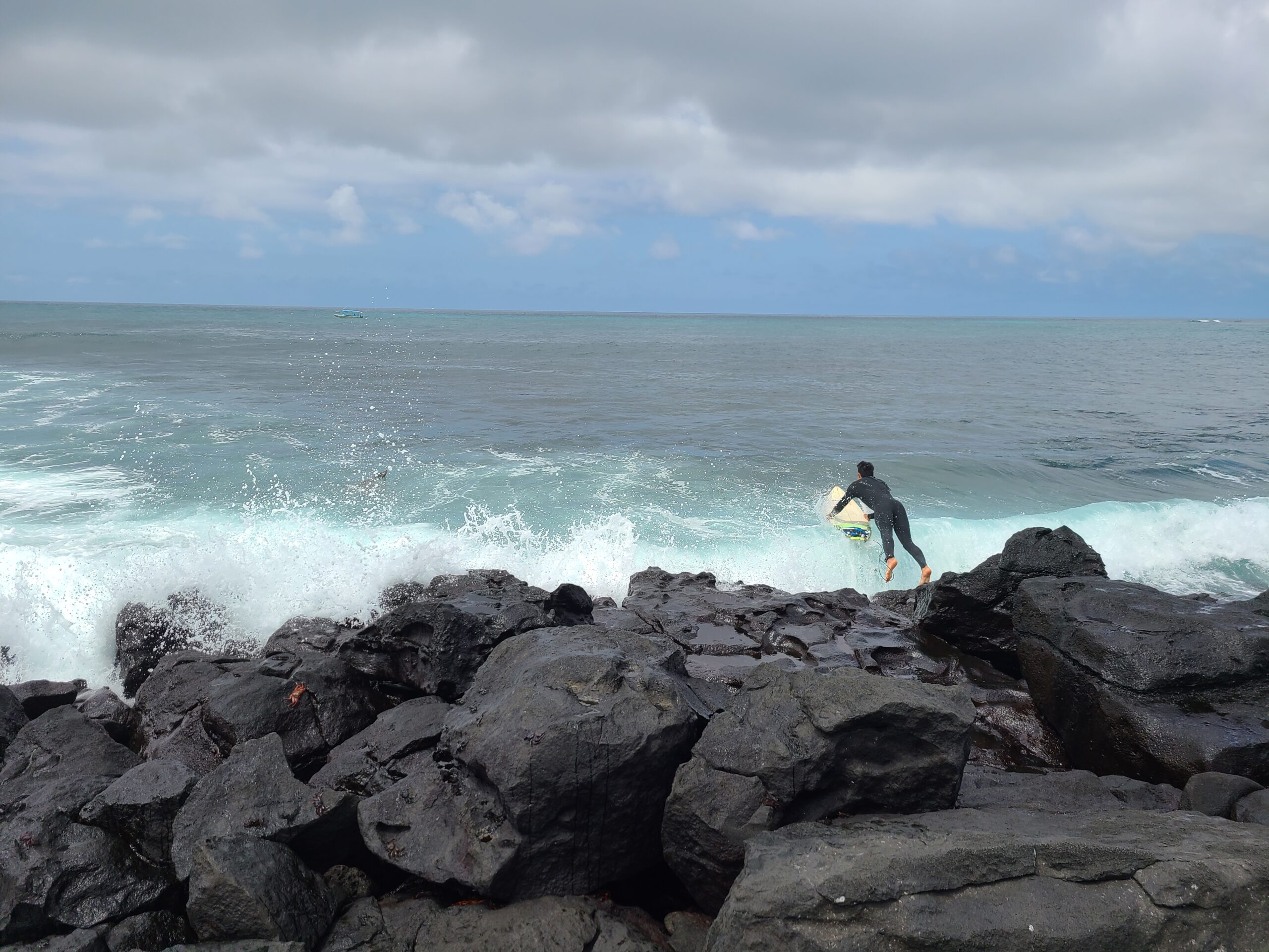 surfer jumping into the ocean at Tongo Reef, San Cristobal, Galapagos