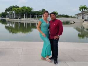 man and woman in wedding attire at scenic location with lake and palm trees