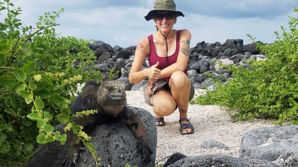 woman kneeling next to galapagos marine iguana