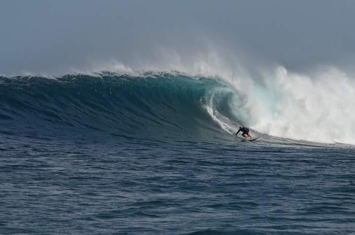 surfer in front of big wave on galapagos surf tour