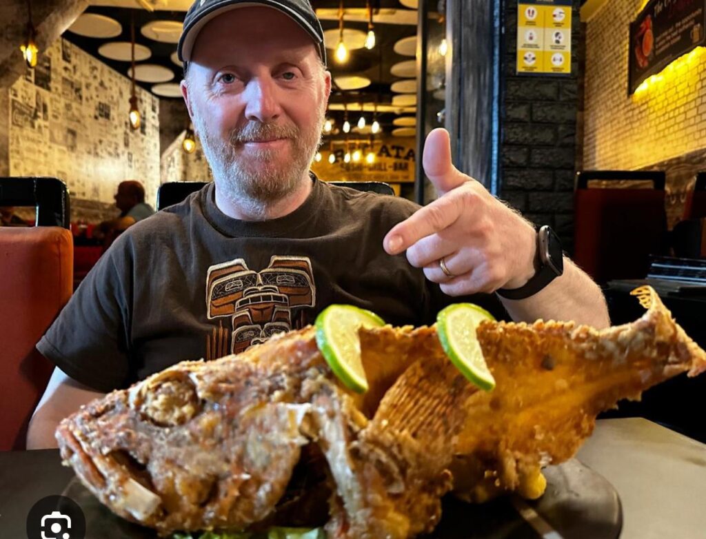 man at Galapagos restaurant with whole fried brujo fish