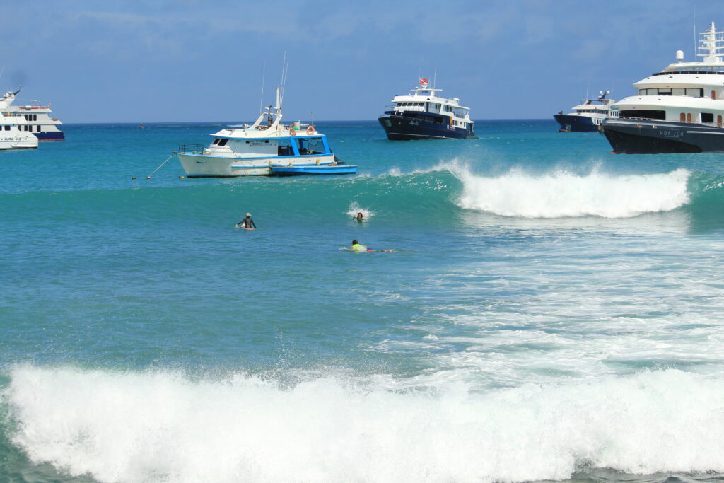 surfers catching a wave at El Faro, San Cristobal, Galapagos