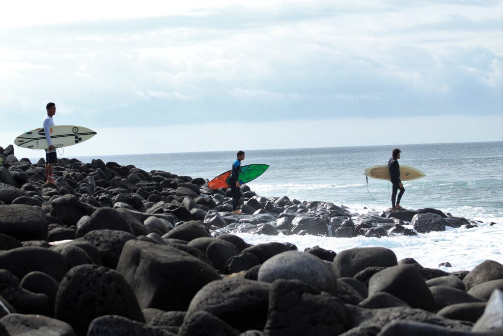 three surfers prepare to enter the water at El Canon, San Cristobal, Galapagos