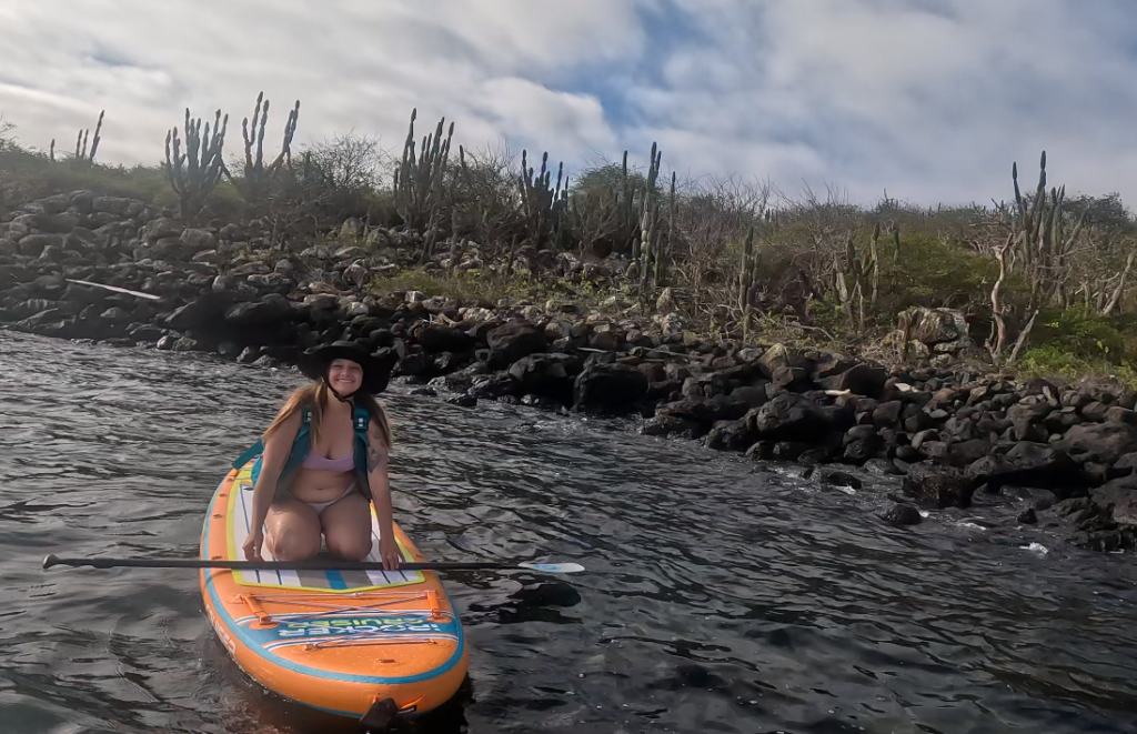 girl kneeling on paddleboard with Opuntia cactus in background