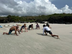 surf instructor doing warmup exercises on a beach during surf lesson in Galapagos